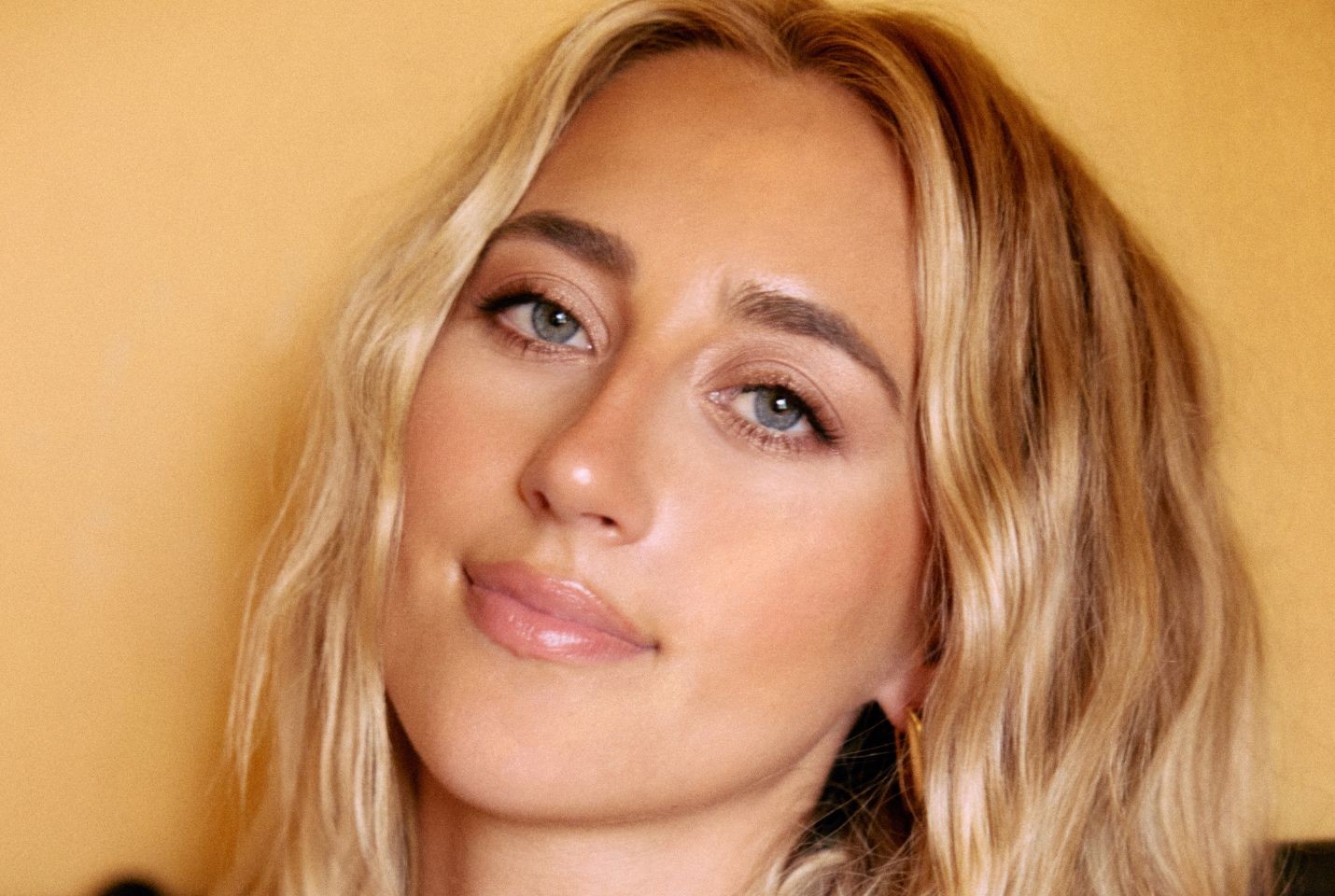 A close up image of a blonde woman with wavy hair